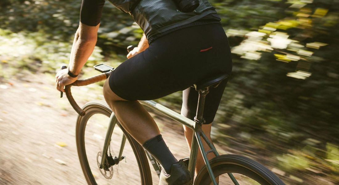 The Wade A man riding a bicycle along a dirt road surrounded by greenery.