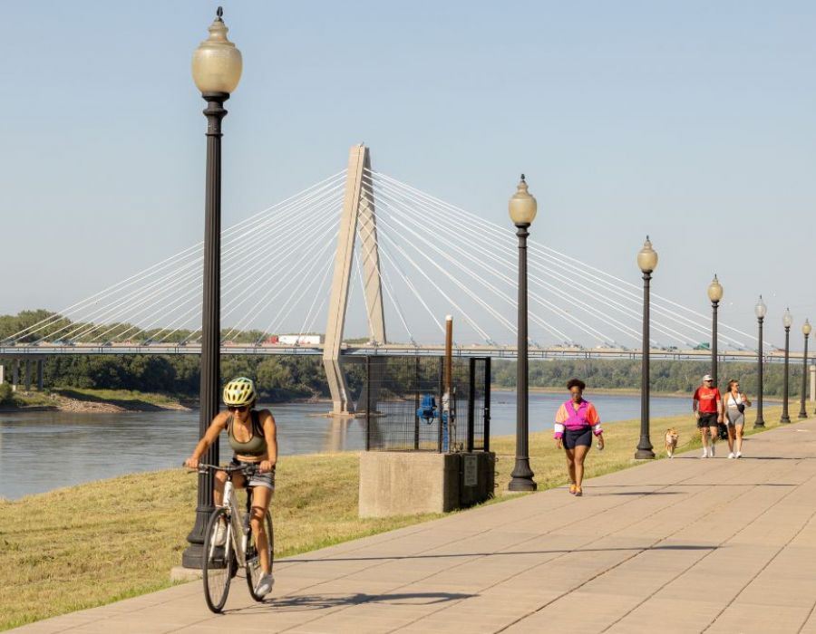 The Wade A group of people riding bicycles along a sidewalk on a sunny day, enjoying outdoor activity together.
