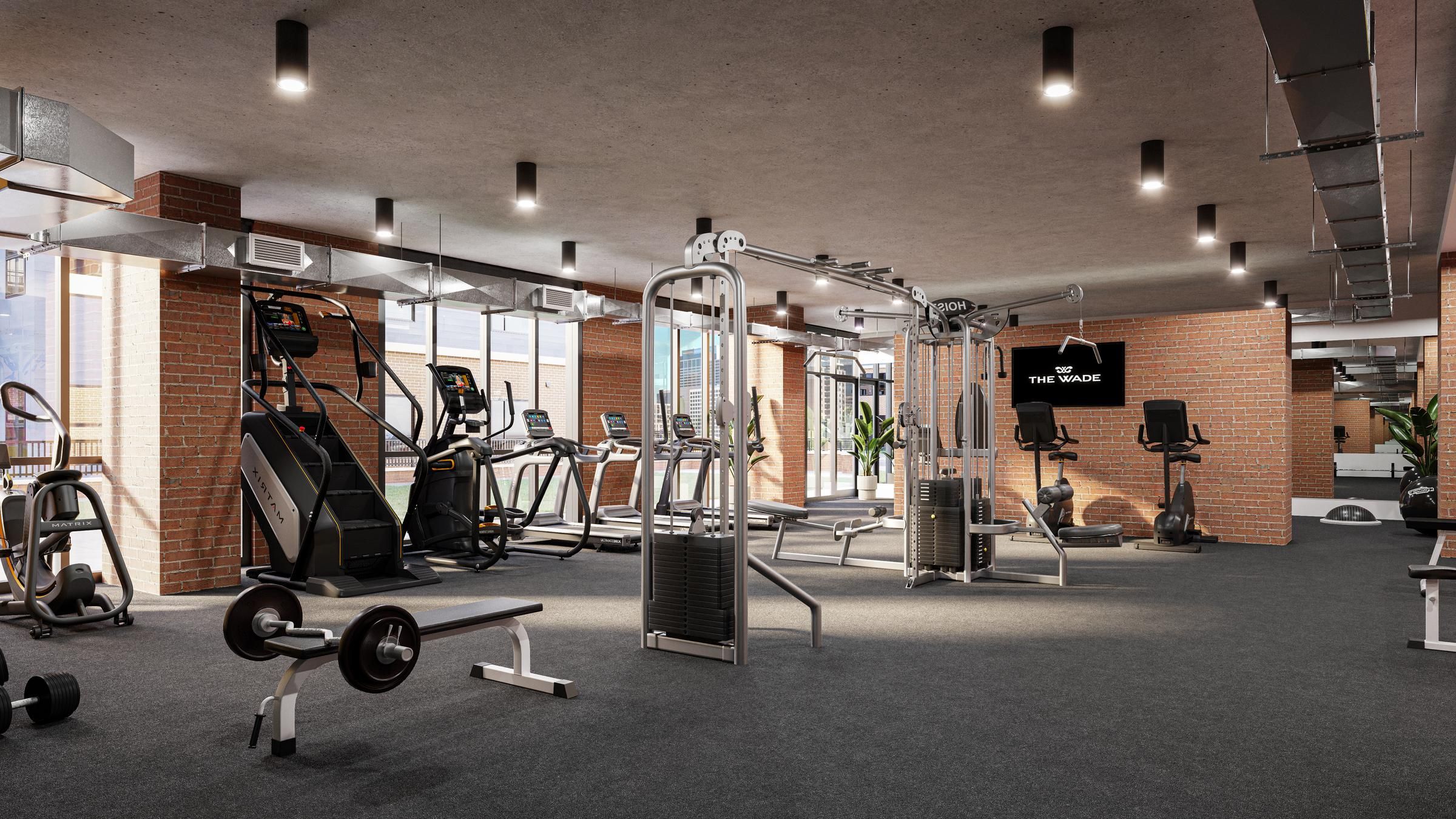 The Wade A gym room featuring various exercise equipment and a large window allowing natural light to enter.