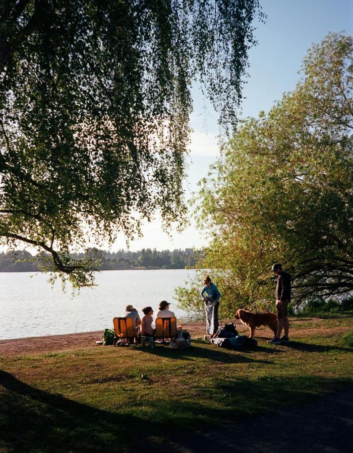 The Wade A group of people gathered around a picnic table by a serene lake, enjoying a meal and each other's company.