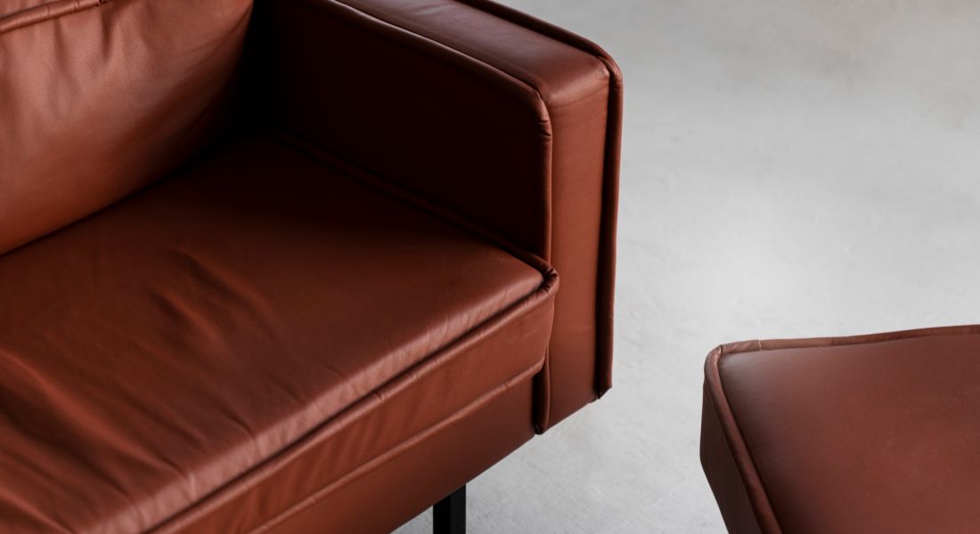 The Wade Close-up of a luxurious leather couch paired with a matching ottoman, showcasing rich texture and craftsmanship.