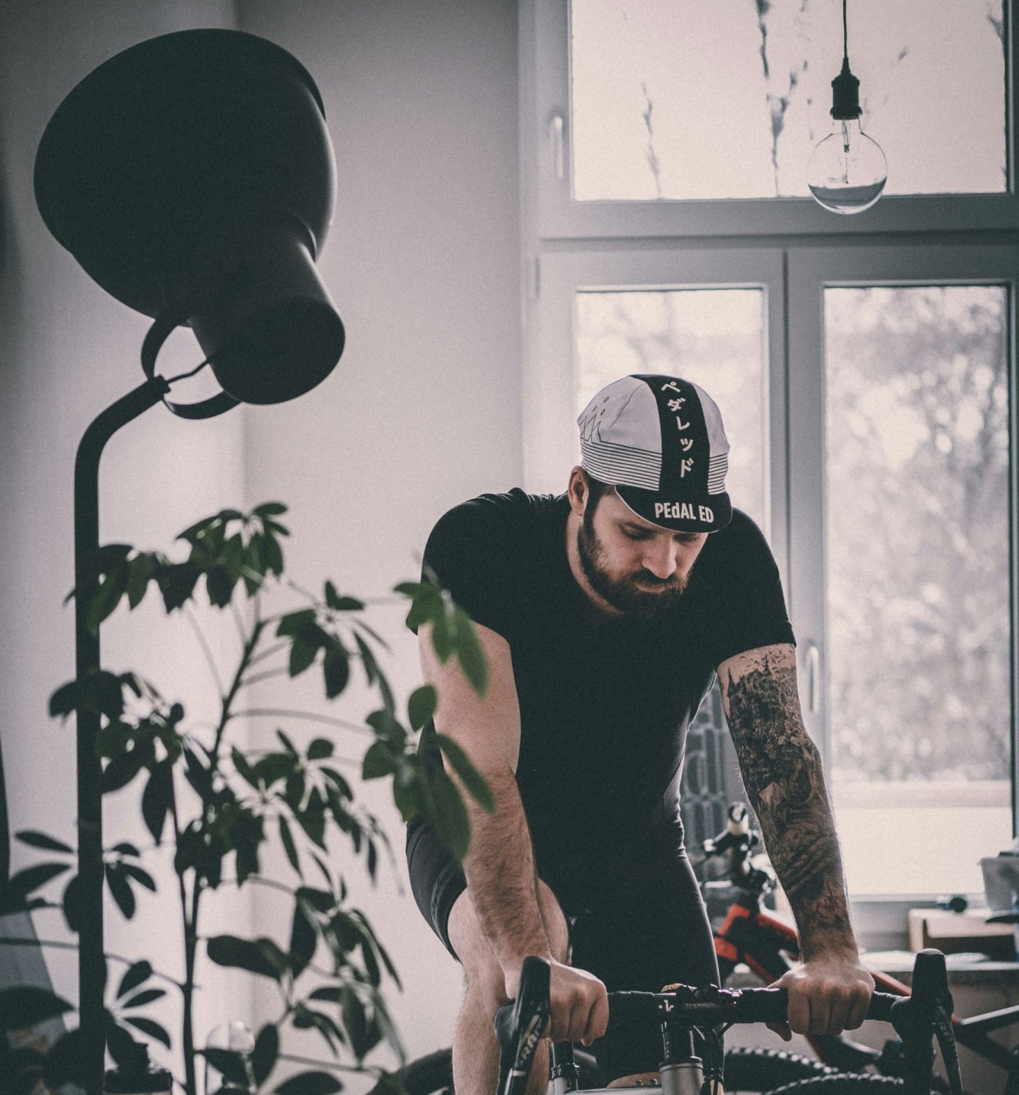 The Wade A man with tattooed arms rides a bicycle, showcasing his tattoos against a vibrant outdoor background.