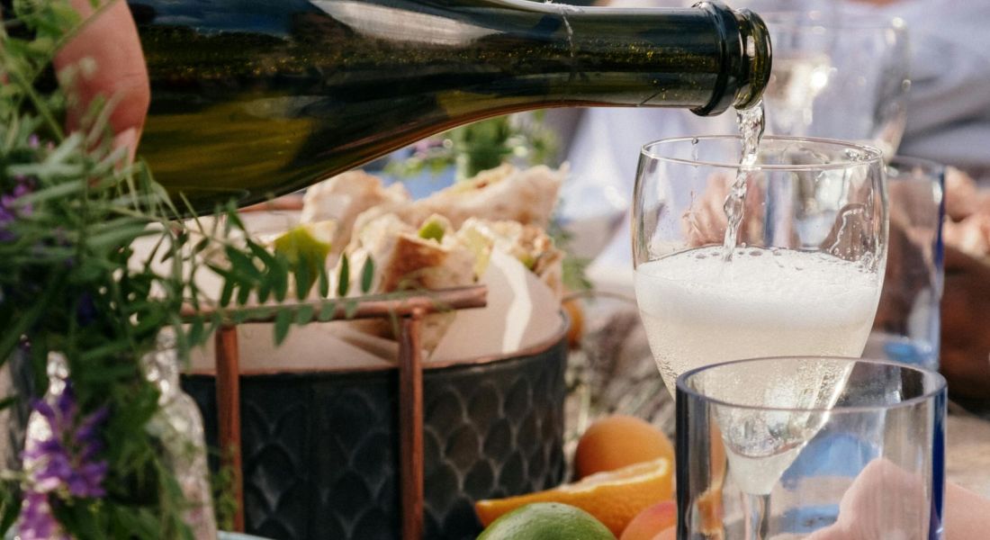 The Wade A woman elegantly pours wine from a bottle into a glass, showcasing a moment of celebration or relaxation.