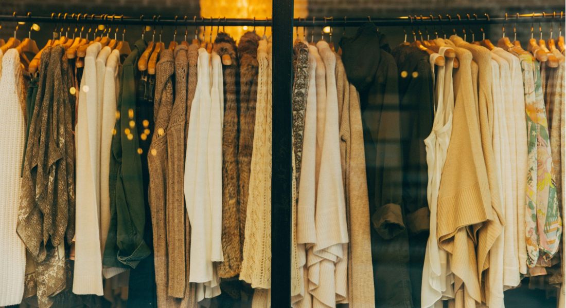 The Wade Clothes of various styles and colors hanging on racks in a well-organized clothing store.